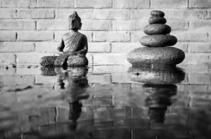 Buddha statue with stacked stones reflecting calmness and balance, symbolizing Buddhism and Minimalism.