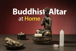 Home Buddhist altar setup featuring a meditating Buddha statue, lit candles, sage bundle, and crystal on a wooden table with the text ‘Buddhist Altar at Home’