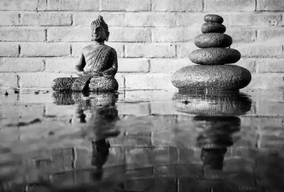 Buddha statue with stacked stones reflecting calmness and balance, symbolizing Buddhism and Minimalism.
